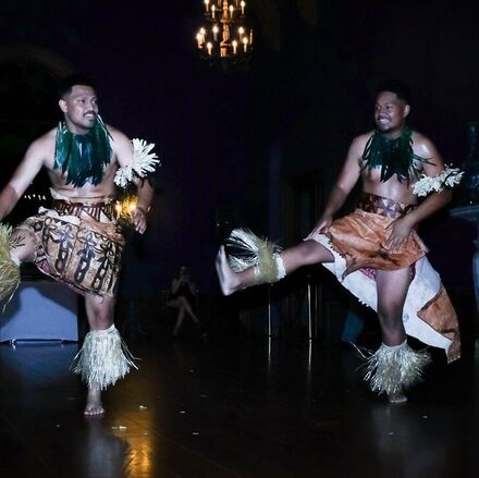 Fijian luau dancers adorned in traditional Fijian attire, featuring ti leaf necklaces, vibrant Fijian skirts, and hau footwear and arm wear, showcasing cultural dance moves.