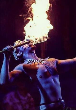 A fire knife dancer, engaging in the traditional art of Siva Afi, demonstrates a daring feat of eating fire. The image captures the intense focus and skill of the performer in this ancient Polynesian practice.